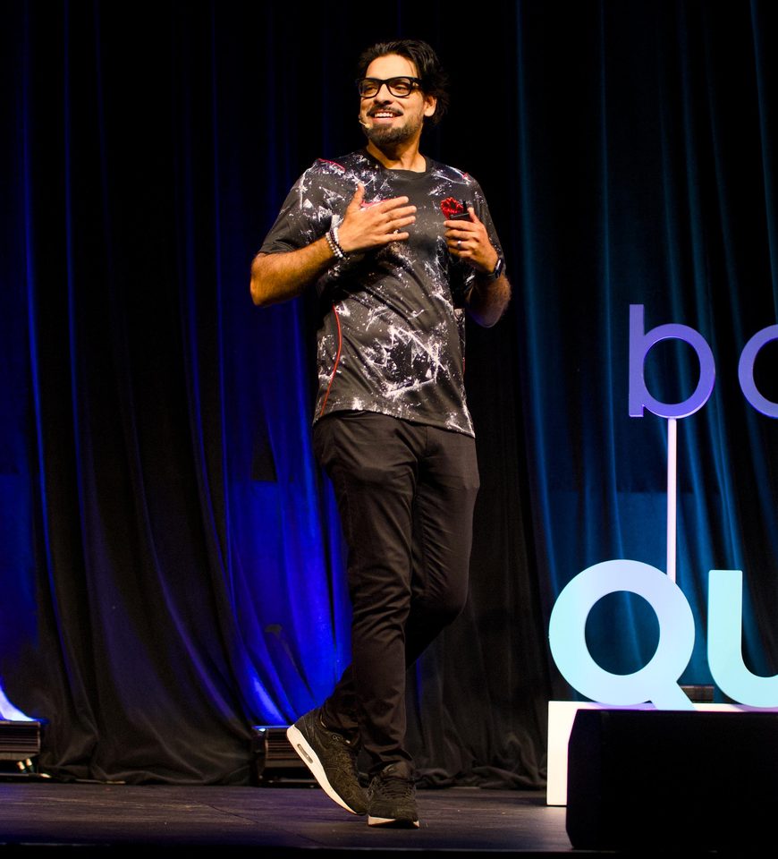 Aizaz Sheikh on stage at the Adventure Travel World Summit in Québec City, wearing a Canada football jersey